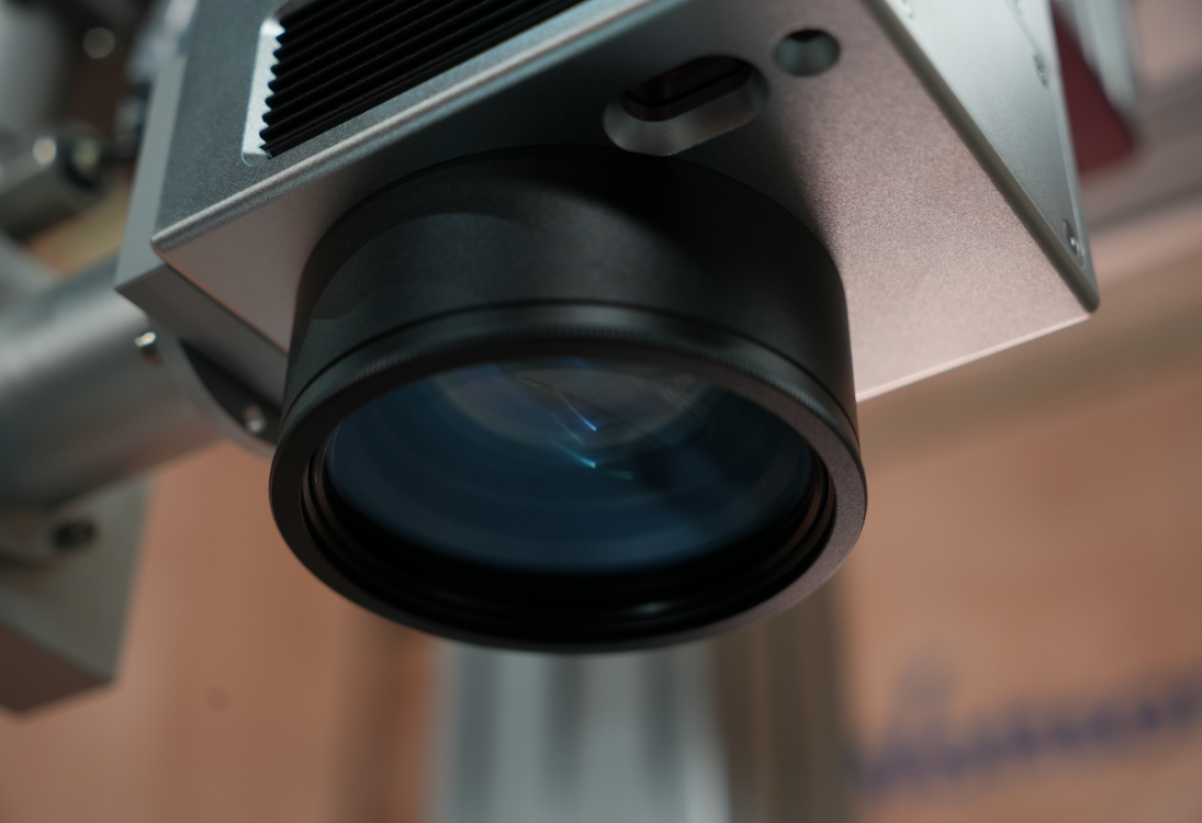 Фокусирующая линза ультрафиолетового (UV) лазерного маркера Wattsan в защитном корпусе, вид снизу.